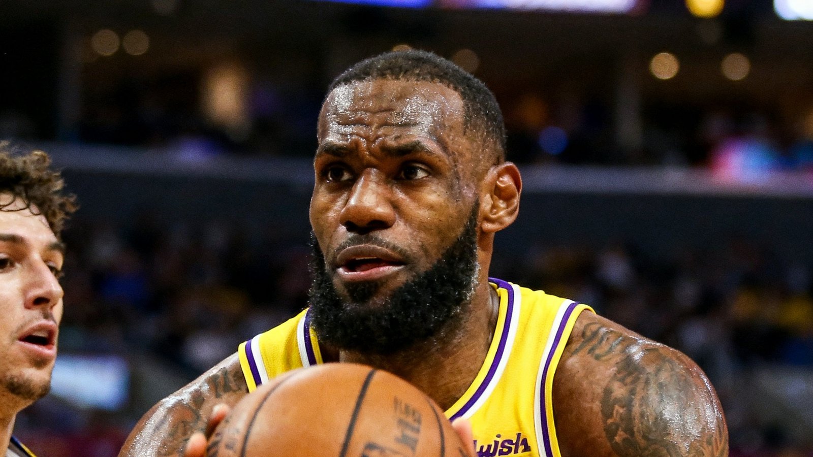 NBA赛场上詹姆斯持球突破防守球员的特写镜头，背景是斯台普斯中心观众席